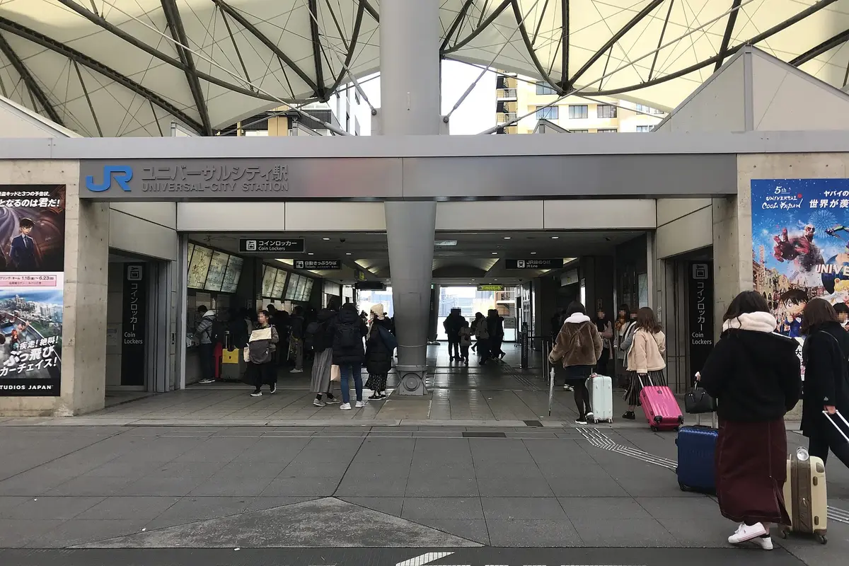 The entrance of JR Universal City Station, a concrete building with a white fabric roof and the station name above the gates